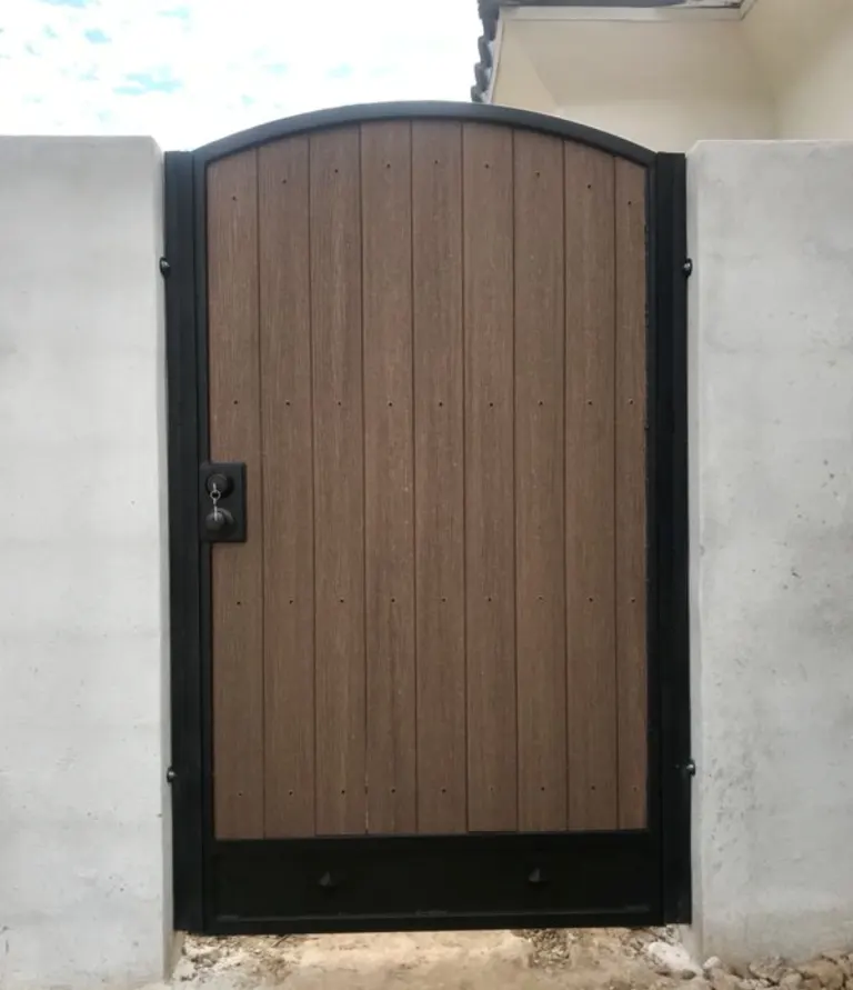 Arched wood and steel yard gate set in a block wall by SG Fabrication
